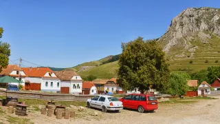 Piața din Rimetea, cu case albe și Piatra Secuiului ridicându-se în fundal